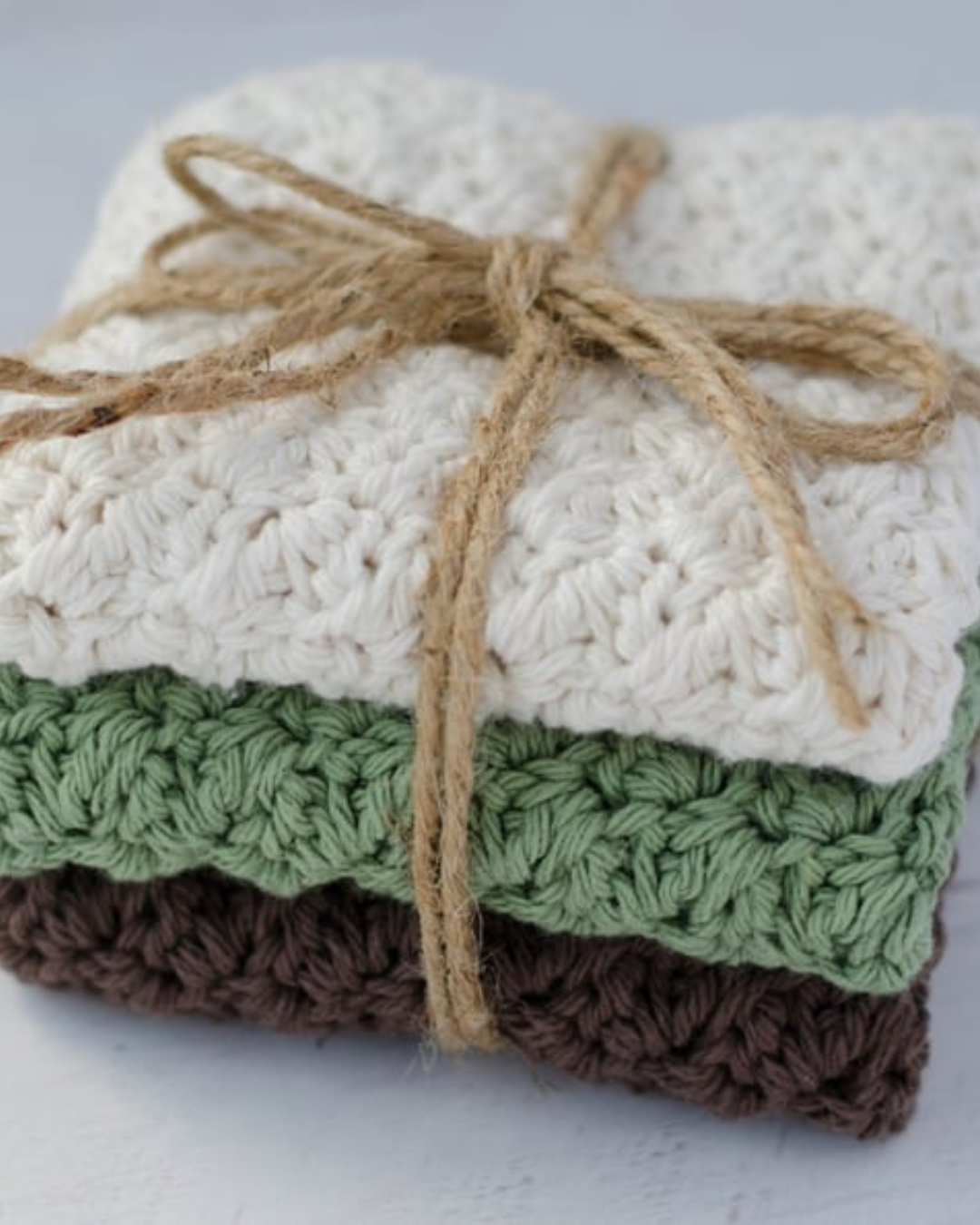 three crochet washcloths wrapped in twine