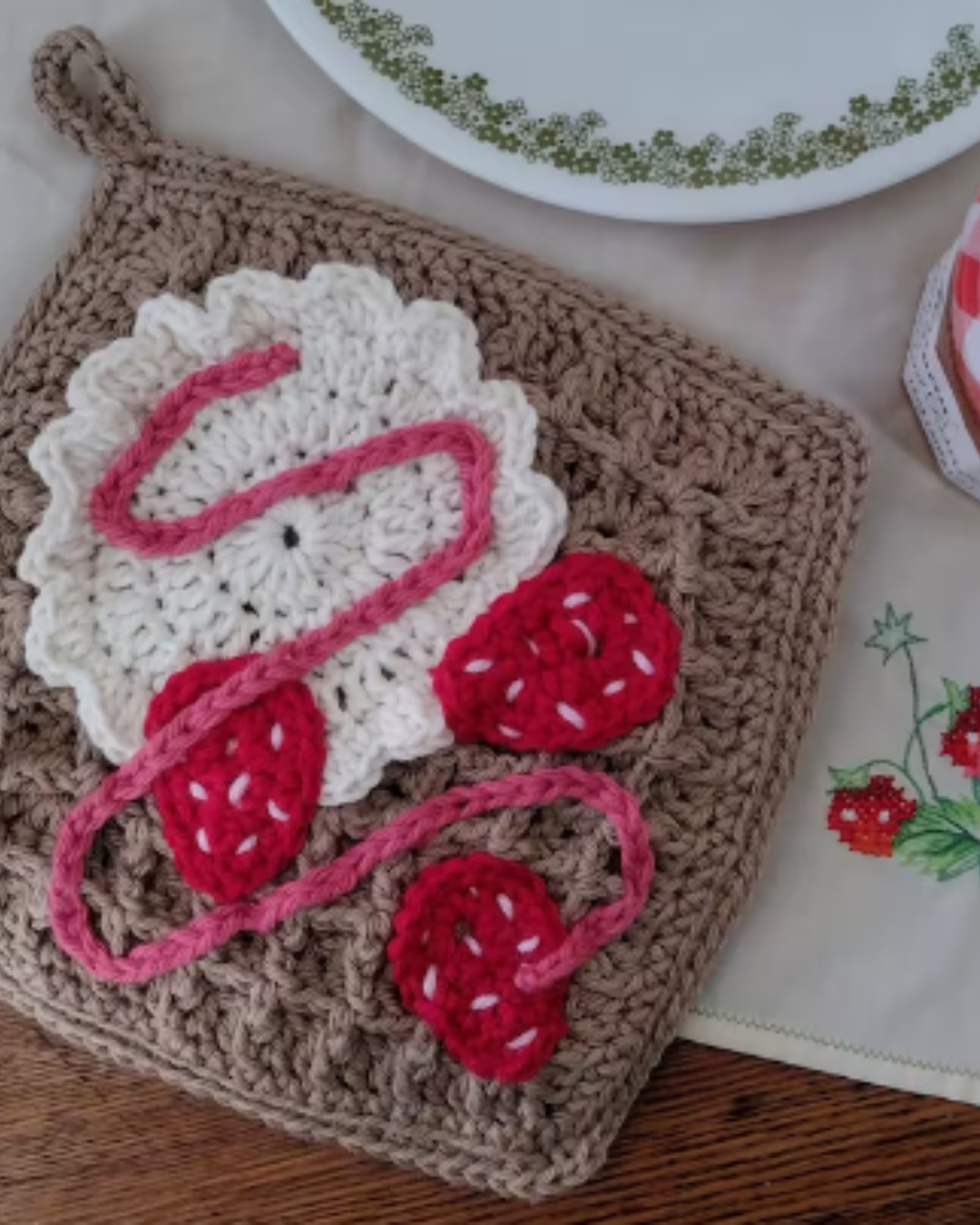 tan crochet waffle stitch potholder with crochet whip cream, strawberries, and drizzle on top